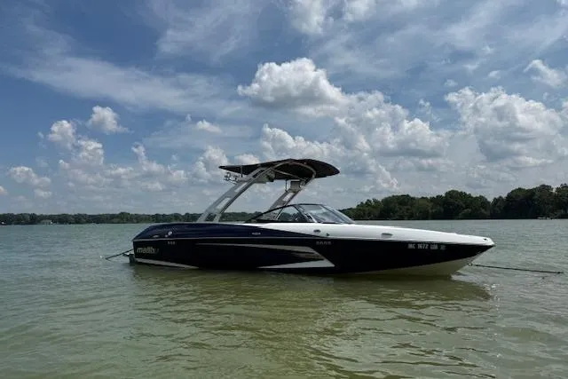Slide: The Image of 2013 Malibu Wakesetter 22 MXZ boat on a calm lake under a cloudy sky. - 2