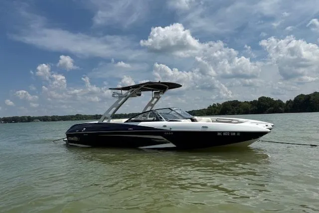 Slide: The Image of 2013 Malibu Wakesetter 22 MXZ boat on a calm lake under a partly cloudy sky. - 5