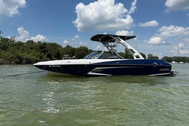 Slide: The Image of 2013 Malibu Wakesetter 22 MXZ boat on calm water under blue sky. - 7