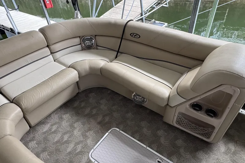 Slide: The Image of Luxurious seating on 2010 Harris Grand Mariner 250 pontoon boat, featuring beige upholstery and cup holders. - 16