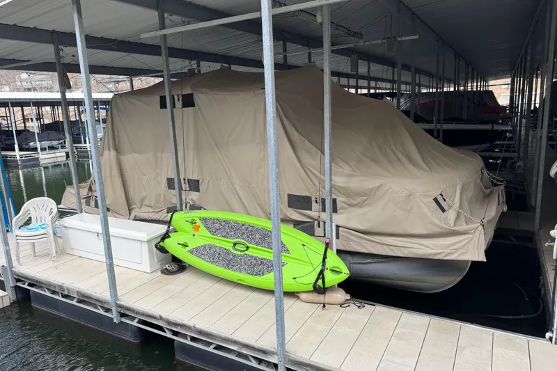 Slide: The Image of Covered 2010 Harris Grand Mariner 250 pontoon boat docked with green paddleboard nearby. - 2