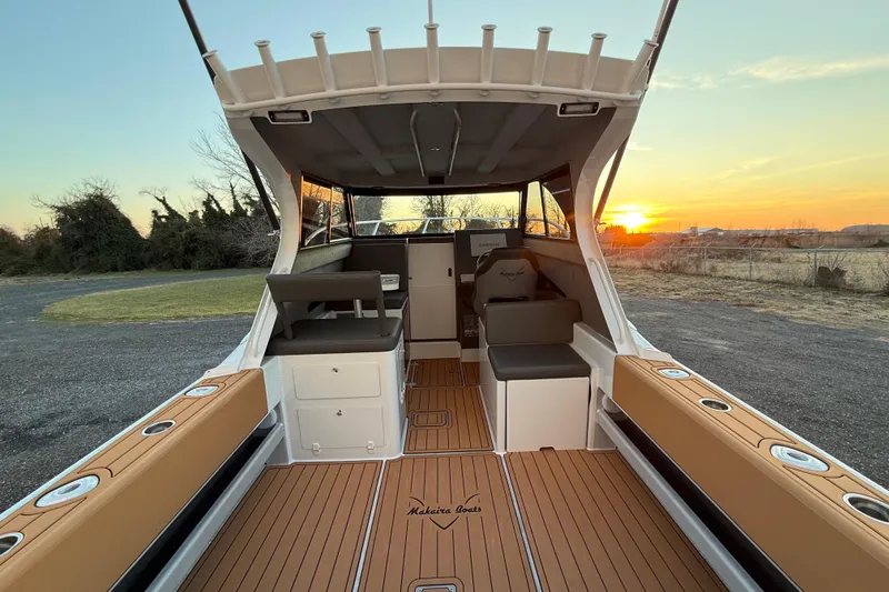Slide: The Image of Makaira Gen3 26 Outboard 2026 boat interior at sunset, featuring sleek seating and wood flooring. - 14