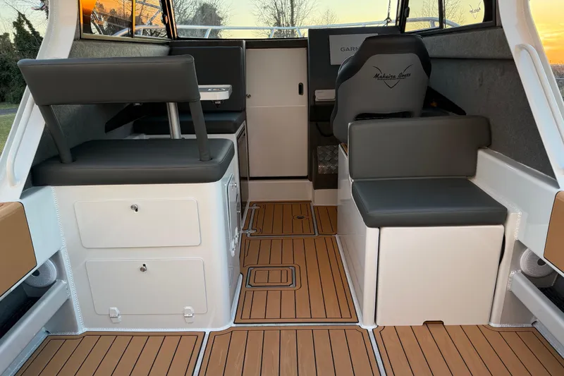 Slide: The Image of Interior of 2026 Makaira Gen3 26 Outboard boat with modern seating and wood flooring. - 16