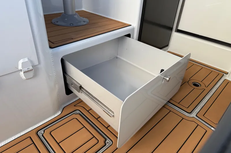 Slide: The Image of Open storage drawer on 2026 Makaira Gen3 26 Outboard boat with teak flooring. - 22