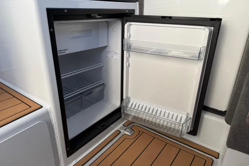 Slide: The Image of Open refrigerator on 2026 Makaira Gen3 26 Outboard boat, featuring removable freezer and storage shelves. - 24