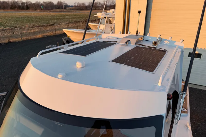 Slide: The Image of 2026 Makaira Gen3 26 Outboard with solar panels on the roof, parked outdoors. - 50