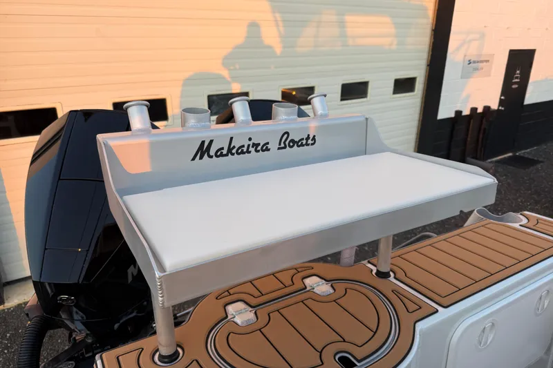 Slide: The Image of Makaira Gen3 26 Outboard 2026 boat with custom deck and motor, docked near a garage. - 52