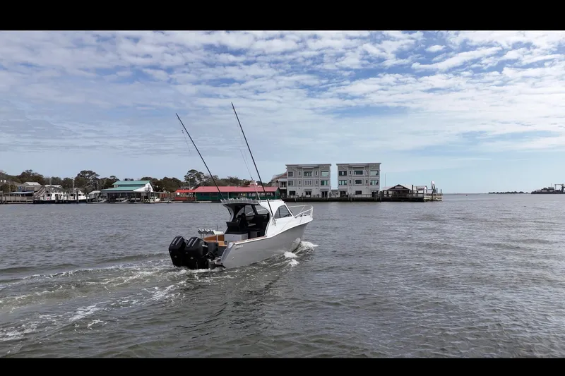 Slide: The Image of 2026 Makaira Gen3 26 Outboard cruising on a scenic waterfront with buildings in the background. - 6