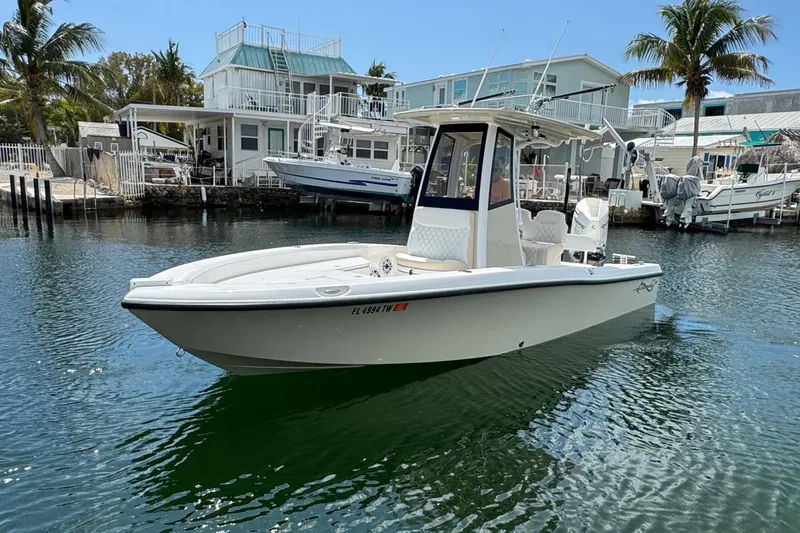 Slide: The Image of 2025 Blackwater 23 Bay boat docked near waterfront homes, surrounded by palm trees. - 2
