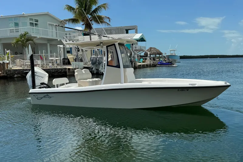 Slide: The Image of 2025 Blackwater 23 Bay boat docked near waterfront homes, under clear blue sky. - 3