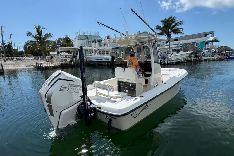 Slide: The Image of 2025 Blackwater 23 Bay boat with powerful engine, docked near palm trees and waterfront homes. - 5