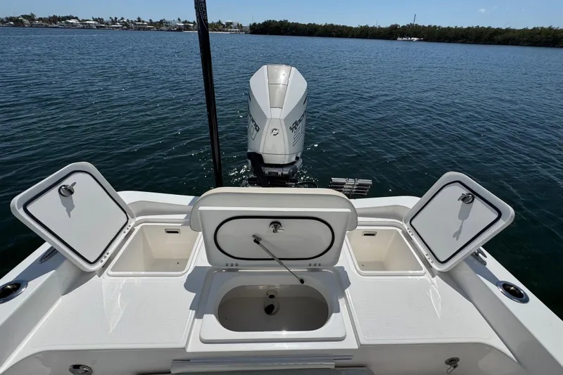 Slide: The Image of 2025 Blackwater 23 Bay boat with open storage compartments and outboard motor on water. - 60
