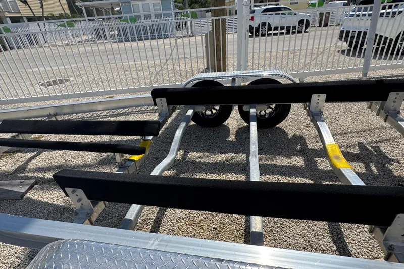 Slide: The Image of Boat trailer for 2025 Blackwater 23 Bay, parked on gravel near a white fence. - 79