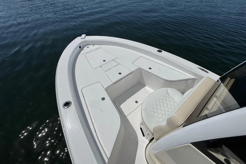 Slide: The Image of 2025 Blackwater 23 Bay boat, white deck, seating, and storage compartments on calm water. - 8