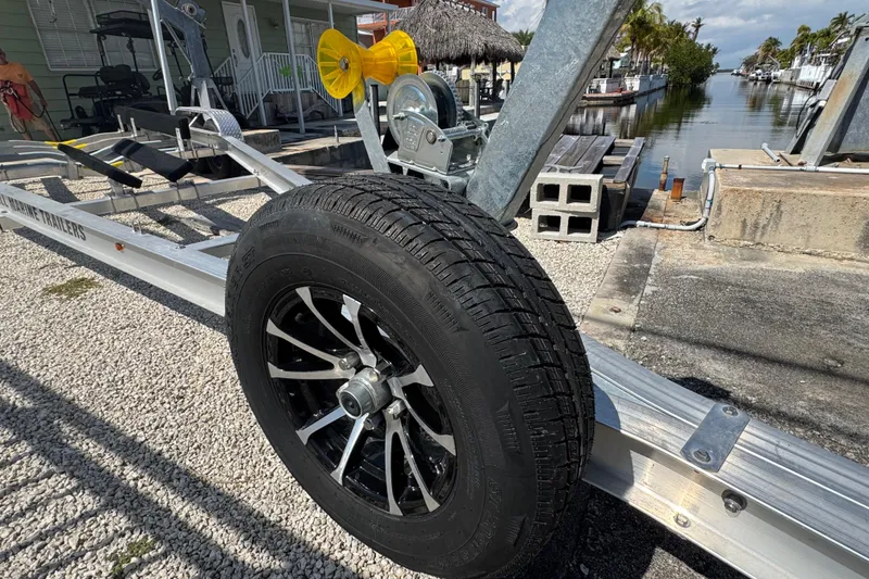 Slide: The Image of Trailer wheel on gravel, near waterway, for 2025 Blackwater 23 Bay boat. - 81