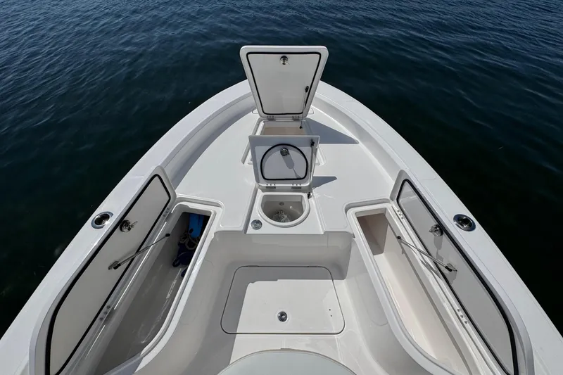 Slide: The Image of 2025 Blackwater 23 Bay boat deck with open storage compartments on calm water. - 9