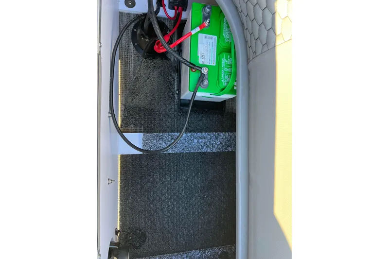 Slide: The Image of 2024 Qwest 8520 DH RLS LT boat battery compartment with wiring and green battery. - 16