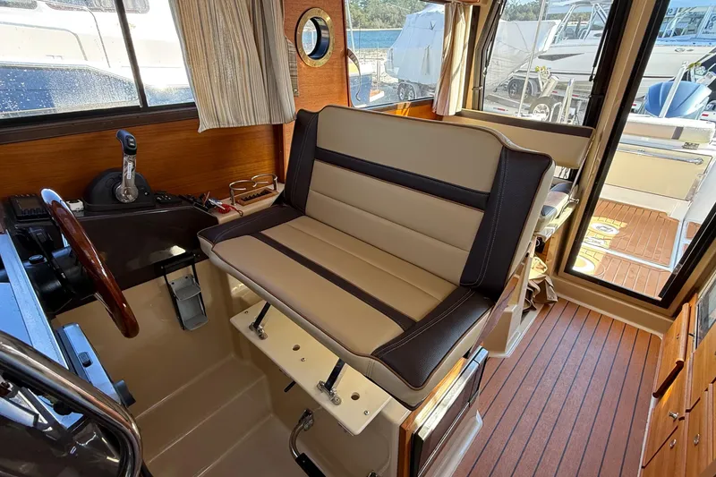 Slide: The Image of 2019 Ranger Tugs R-27 interior helm with cushioned seating and wooden accents. - 10