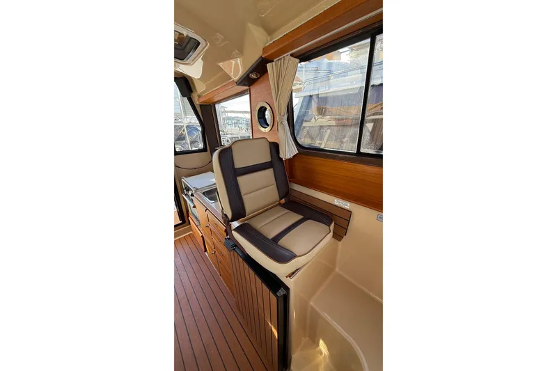 Slide: The Image of 2019 Ranger Tugs R-27 interior with cushioned seating and wood accents. - 13