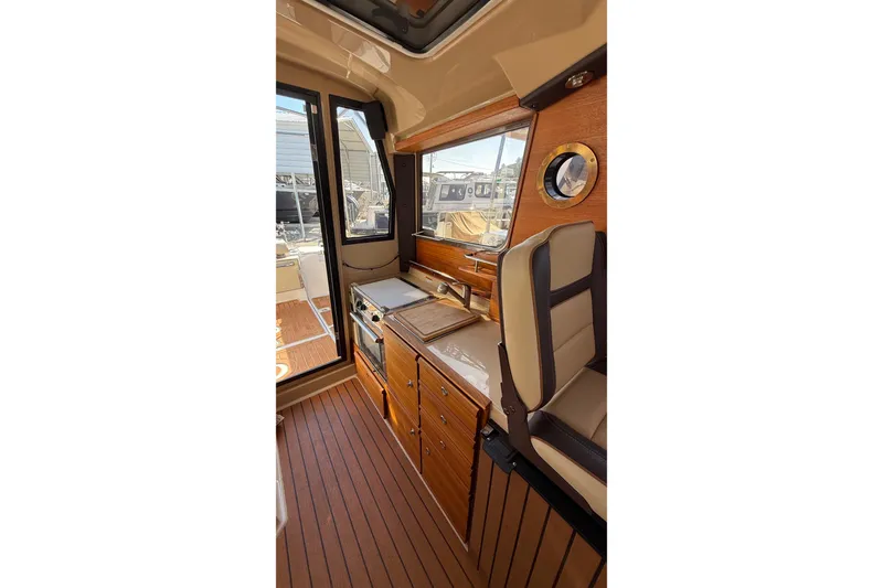 Slide: The Image of 2019 Ranger Tugs R-27 interior with wood finish and compact kitchen area. - 14