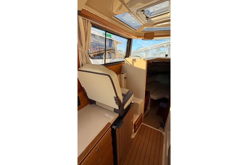 Slide: The Image of 2019 Ranger Tugs R-27 interior with helm seat, wood accents, and cabin view. - 16