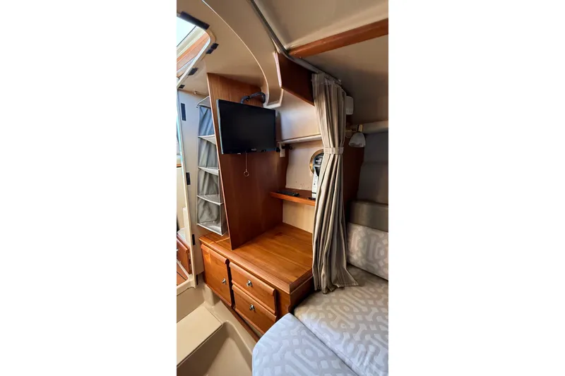 Slide: The Image of 2019 Ranger Tugs R-27 interior with TV, wooden cabinetry, and cozy seating area. - 20