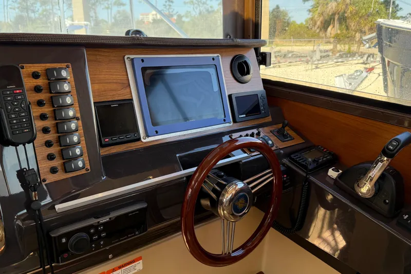 Slide: The Image of 2019 Ranger Tugs R-27 helm with navigation controls, steering wheel, and communication devices. - 8