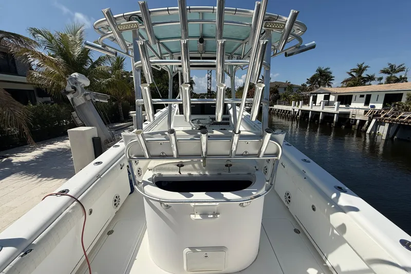 Slide: The Image of 2003 Palmetto 33 Adventure boat docked by waterfront homes, featuring rod holders and a spacious deck. - 12