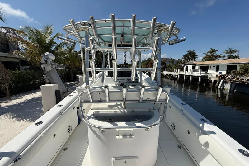 Slide: The Image of 2003 Palmetto 33 Adventure boat docked by waterfront homes, featuring a spacious deck and rod holders. - 9