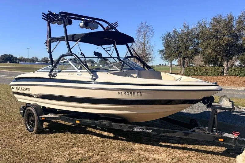 The Image of 2004 Larson LXH 190 I/O boat on trailer, parked outdoors on grass. - 0