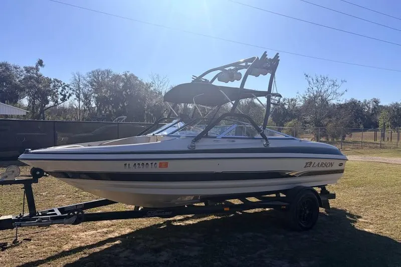 Slide: The Image of 2004 Larson LXH 190 I/O boat on trailer, parked outdoors under clear sky. - 2