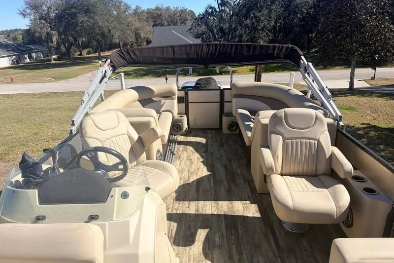 Slide: The Image of 2016 Crest II 230 SLC pontoon boat with beige seating and canopy, parked on grass. - 19