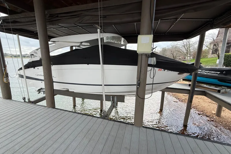 The Image of 2024 Regal LS4 boat docked under a covered lift by the water. - 0