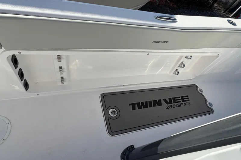 Slide: The Image of 2026 Twin Vee 280 GFX2 CC boat interior, featuring storage compartments and branded flooring. - 8
