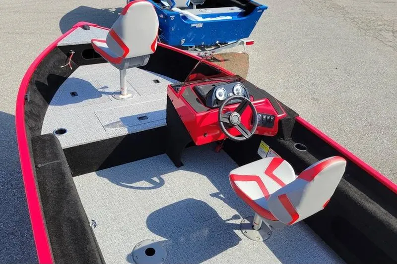 Slide: The Image of 2026 Smoker Craft Lazer 161 boat interior with red and gray seating and steering console. - 3