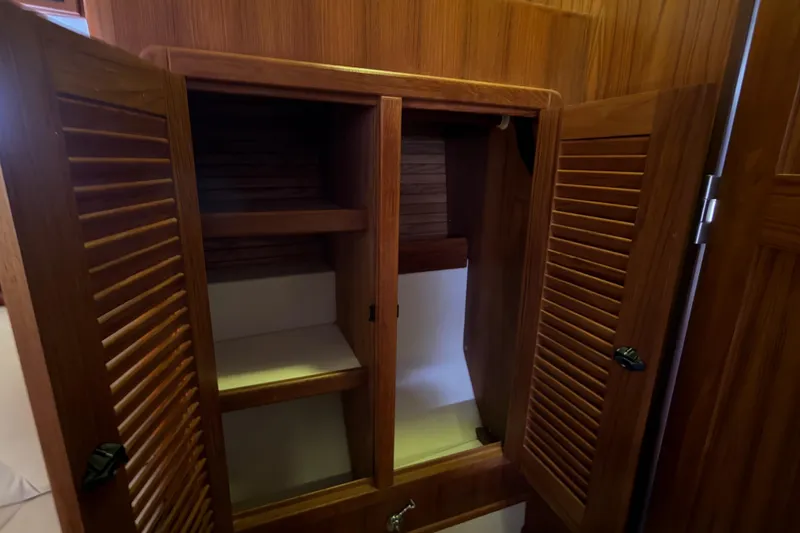 Slide: The Image of Wooden cabinet interior on a 1998 Catalina 380 sailboat, featuring shelves and louvered doors. - 33