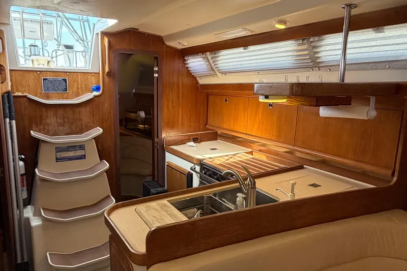 Slide: The Image of Interior of 1998 Catalina 380 sailboat with wooden cabinetry and compact kitchen area. - 8