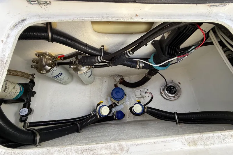 Slide: The Image of 2023 Cape Horn 32 XS boat compartment with hoses, filters, and wiring. - 54