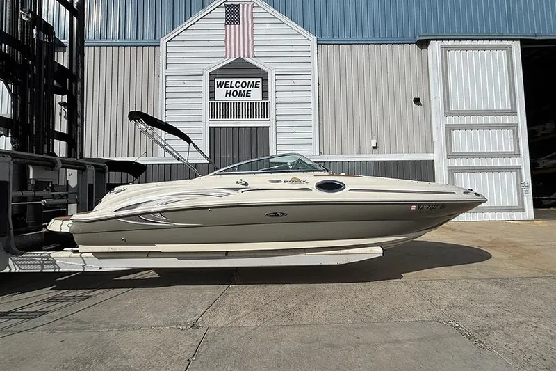 The Image of 2005 Sea Ray 240 Sundeck boat docked at a marina with "Welcome Home" sign. - 0