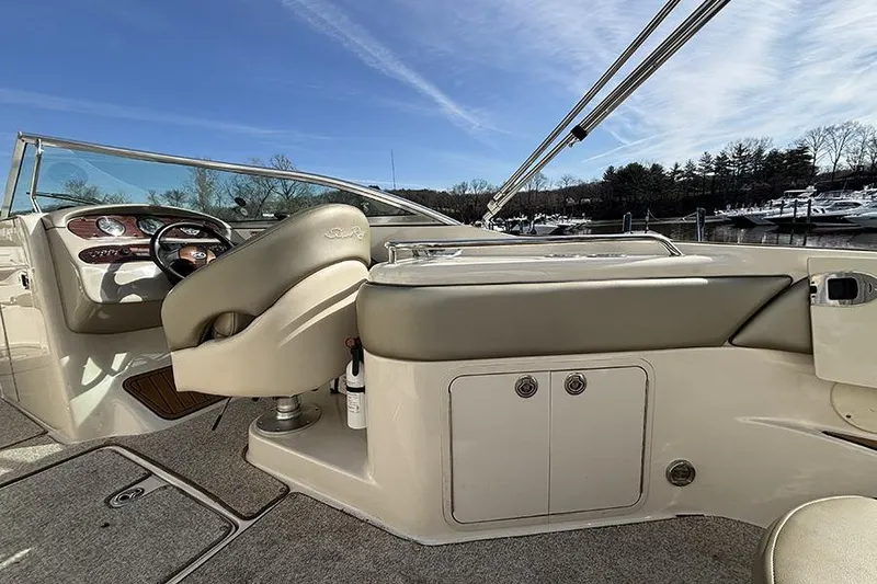 Slide: The Image of 2005 Sea Ray 240 Sundeck interior with helm and seating, under clear blue sky. - 10