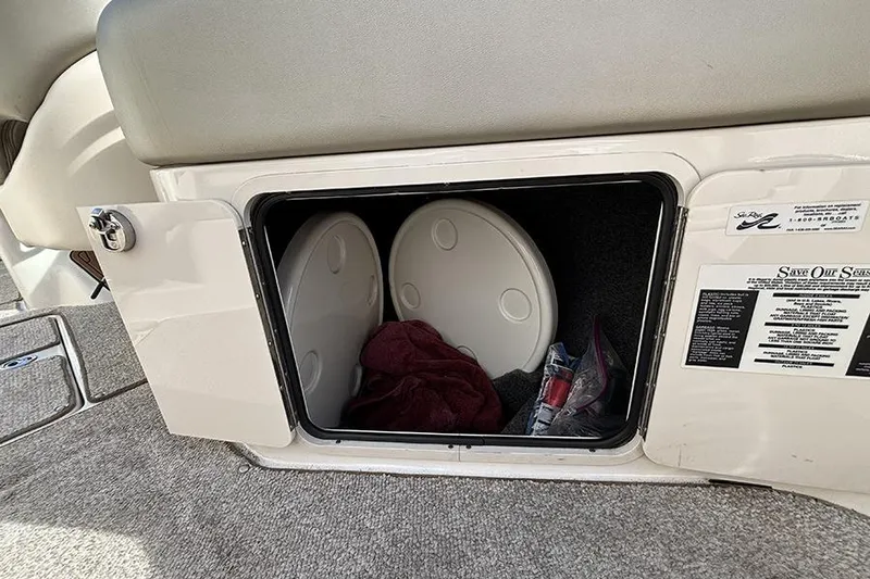 Slide: The Image of Storage compartment in a 2005 Sea Ray 240 Sundeck boat, containing life jackets and towels. - 11