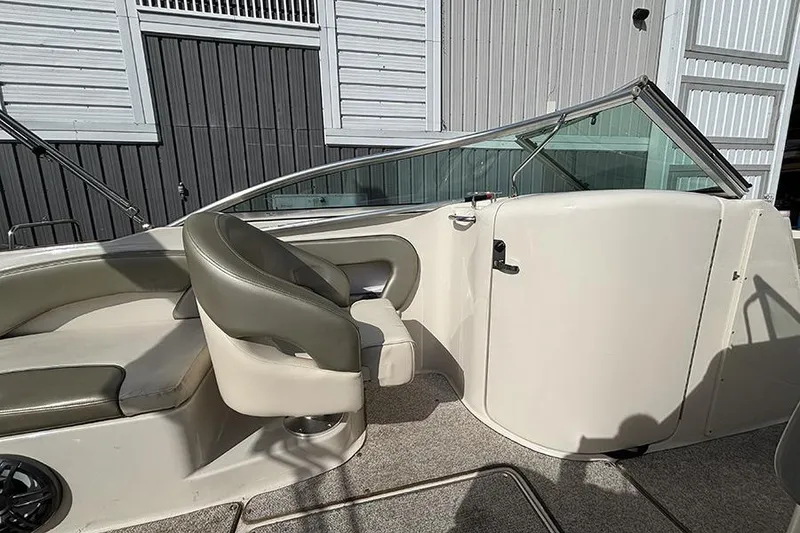 Slide: The Image of 2005 Sea Ray 240 Sundeck interior with seating and windshield, docked near a building. - 13