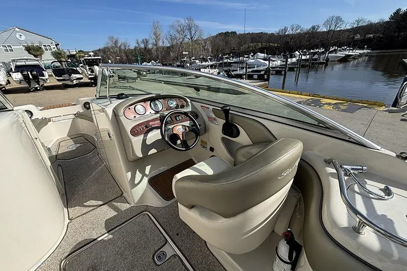 Slide: The Image of 2005 Sea Ray 240 Sundeck boat interior with steering wheel and dashboard, docked by a marina. - 18