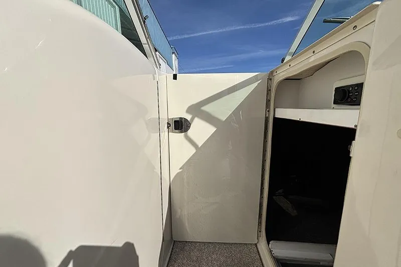 Slide: The Image of 2005 Sea Ray 240 Sundeck interior with open cabin door under clear blue sky. - 22