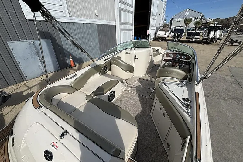 Slide: The Image of 2005 Sea Ray 240 Sundeck boat interior with seating and dashboard, docked near a marina. - 5