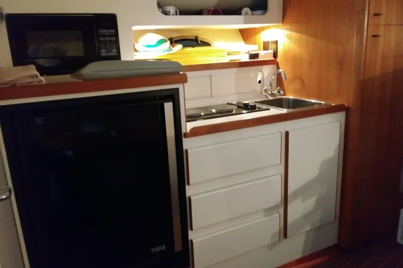 Slide: The Image of Compact kitchen area in a 1993 Tiara 3100 Open boat, featuring a sink and stove. - 24