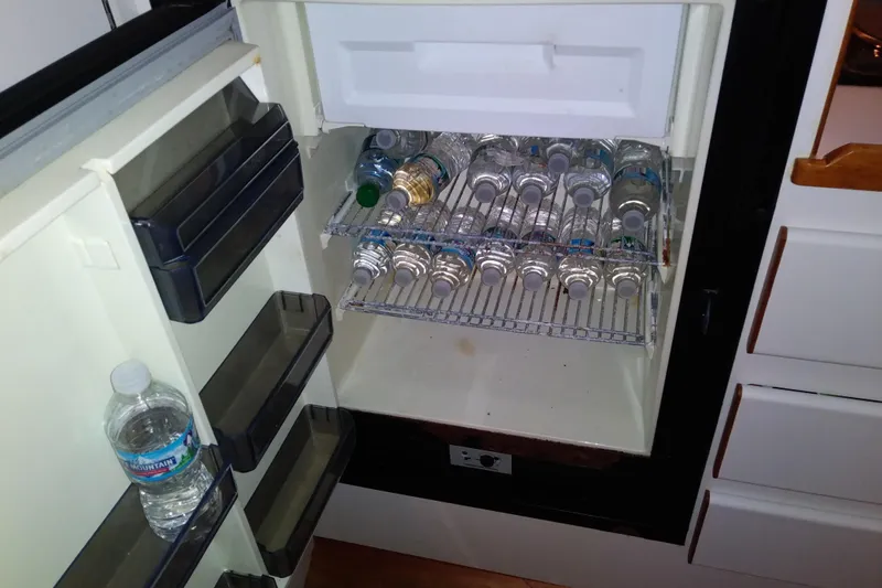 Slide: The Image of Refrigerator stocked with water bottles inside a 1993 Tiara 3100 Open boat. - 25