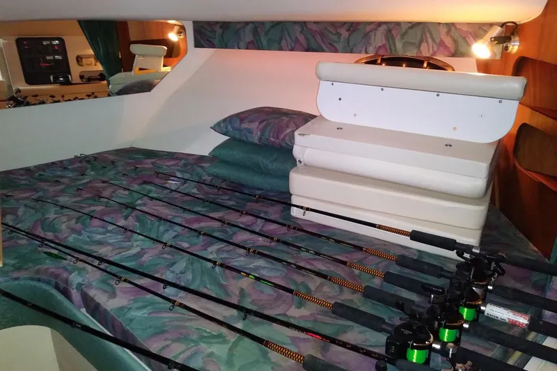 Slide: The Image of Interior of a 1993 Tiara 3100 Open boat with fishing rods on a patterned bed. - 26