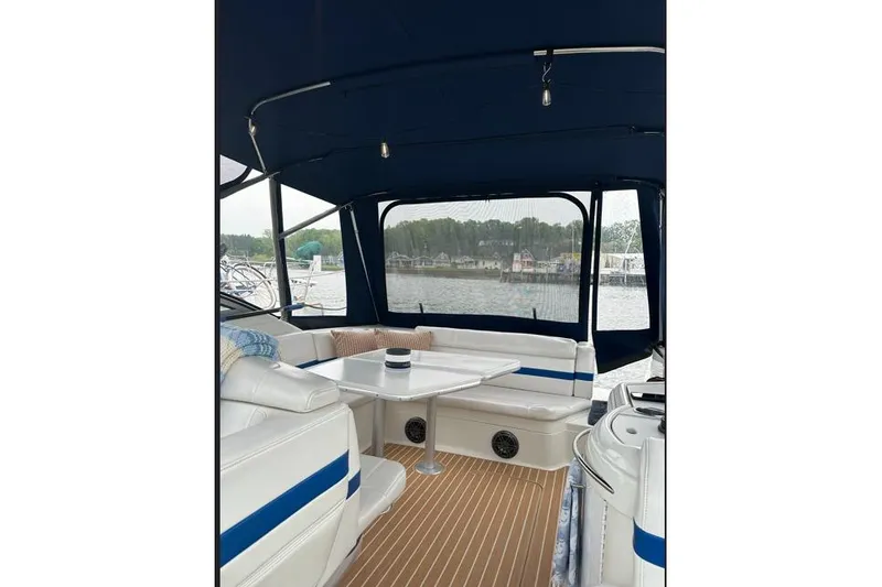 Slide: The Image of 2002 Formula 330 Sun Sport boat interior with seating and table, docked by the water. - 11