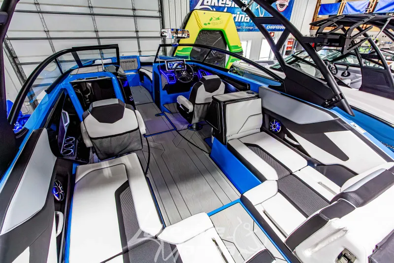 Slide: The Image of 2023 Yamaha Boats 255XE interior with modern seating and sleek design in a showroom. - 19